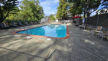 a swimming pool with chairs and a fence around it at Trailhead Apartments at Tam Junction, Mill Valley